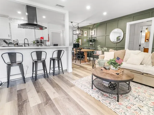 a living room with furniture a wooden floor and kitchen view