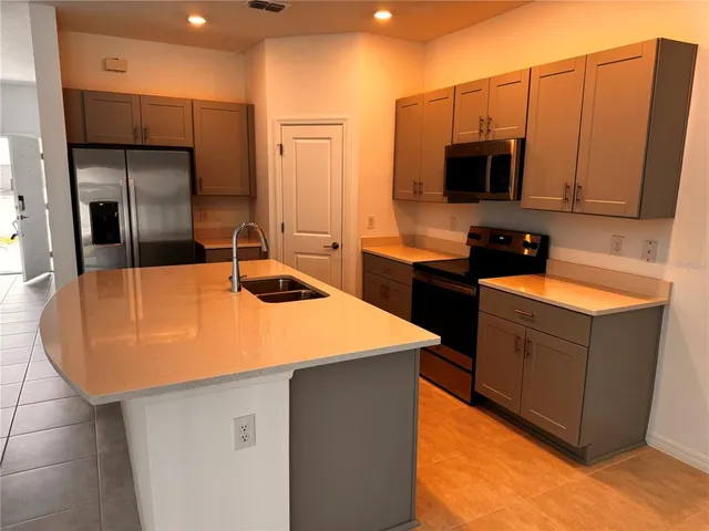 a kitchen with stainless steel appliances a sink a microwave a refrigerator and white cabinets