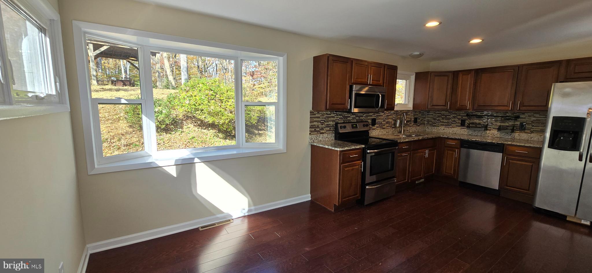 7613 Locust Lane Fort Washington, MD 20744 - Photo 18 of 49 a kitchen with stainless steel appliances granite countertop wooden floors a stove a sink a microwave and cabinets