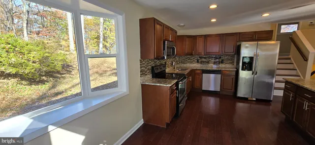 a kitchen with refrigerator a stove and wooden floor
