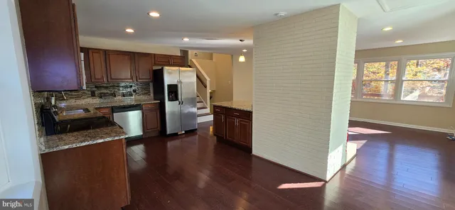 a kitchen with stainless steel appliances granite countertop a refrigerator sink and wooden floor