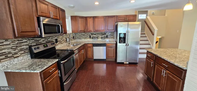 a kitchen with stainless steel appliances granite countertop a refrigerator a stove top oven a sink and dishwasher