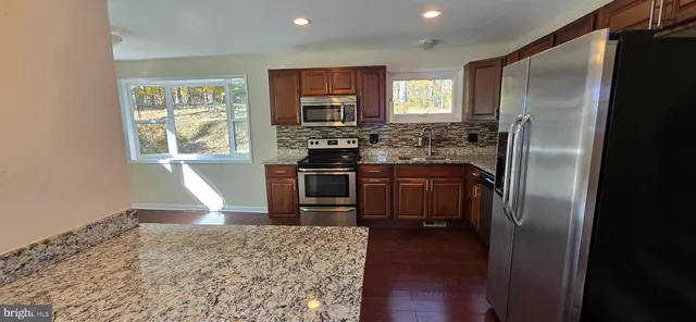 a kitchen with stainless steel appliances granite countertop a refrigerator stove and sink