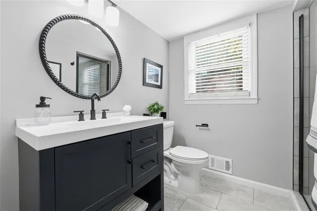 a bathroom with a sink a mirror a toilet and a window