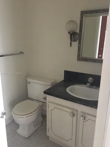 a bathroom with a granite countertop toilet sink and mirror