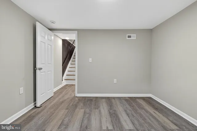 a view of an empty room with wooden floor and stairs