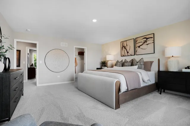 a spacious bedroom with a bed a mirror with dresser and mirror