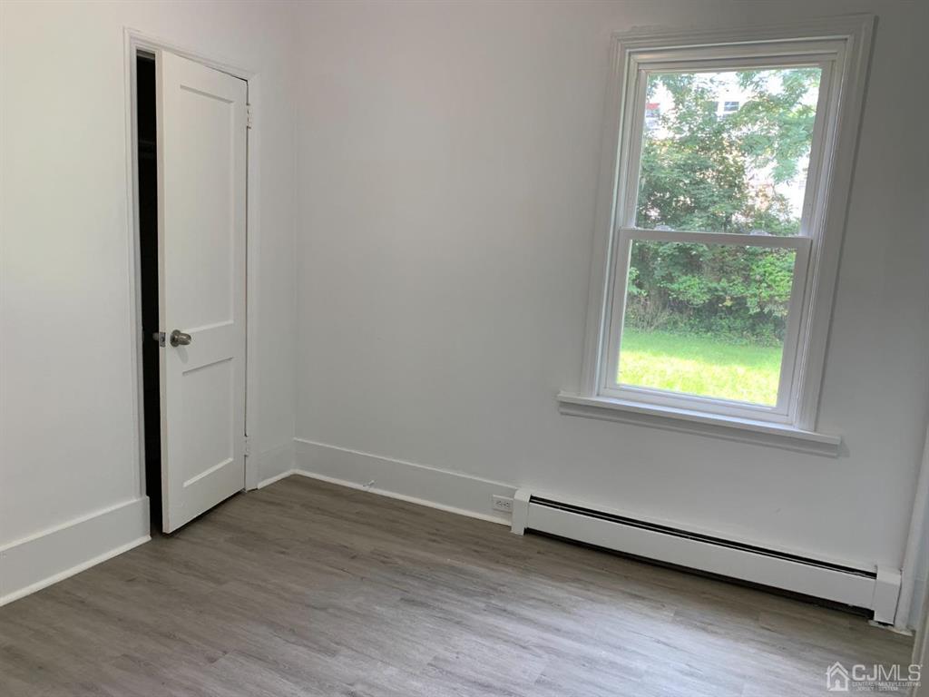 13 Melbourne Court, Unit 1 Woodbridge, NJ 07095 - Photo 6 of 11 an empty room with wooden floor and windows