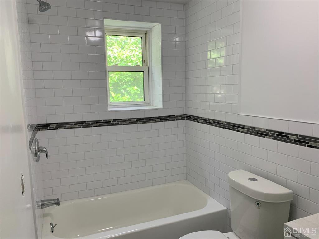 13 Melbourne Court, Unit 1 Woodbridge, NJ 07095 - Photo 9 of 11 a bathroom with a granite countertop bathtub and a toilet