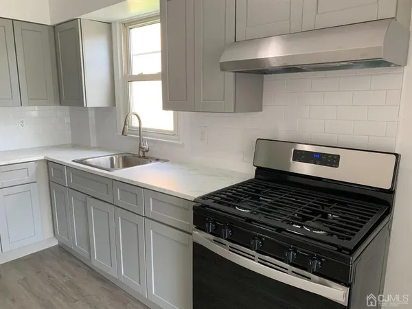 a kitchen with stainless steel appliances a stove and white cabinets