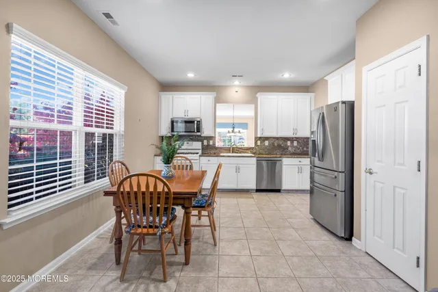 a kitchen with stainless steel appliances a refrigerator a stove a sink and white cabinets with wooden floors