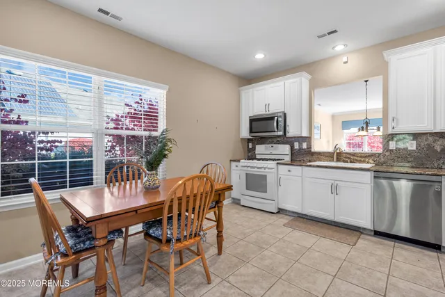 a kitchen with granite countertop a table chairs microwave and cabinets