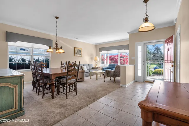 a view of a dining room and livingroom furniture wooden floor a rug a fireplace and a chandelier