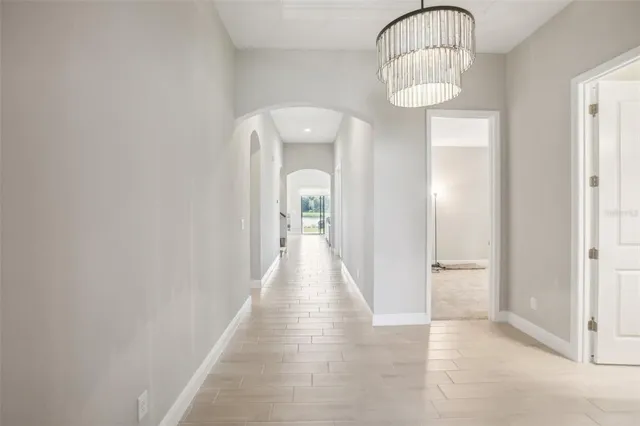 a view of a hallway with wooden floor and chandelier