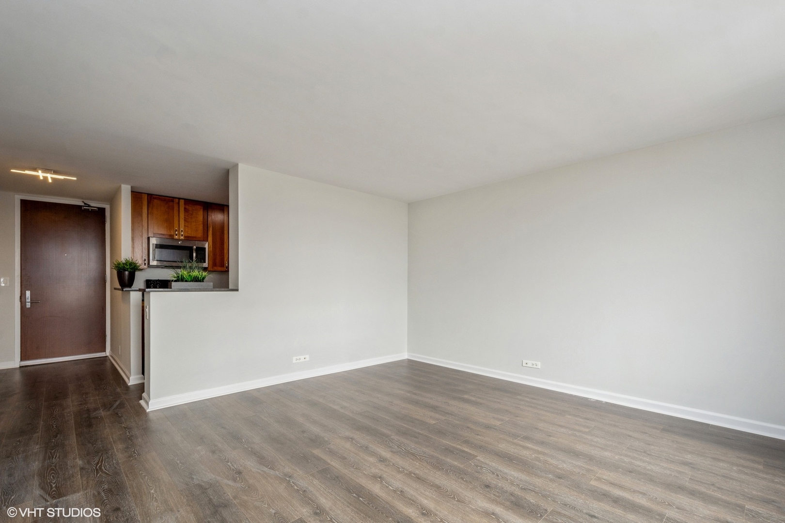655 West Irving Park Road, Unit 5511 Chicago, IL 60613 - Photo 3 of 29 a view of a big room with wooden floor and a kitchen