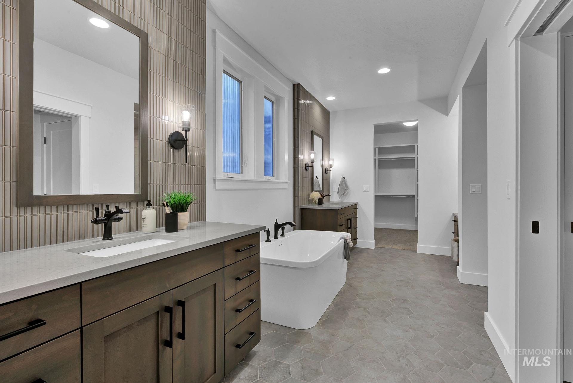 1911 West Timberstone Drive Eagle, ID 83616 - Photo 7 of 15 Full bathroom with a spacious closet, two vanities, recessed lighting, a freestanding tub, and tile walls