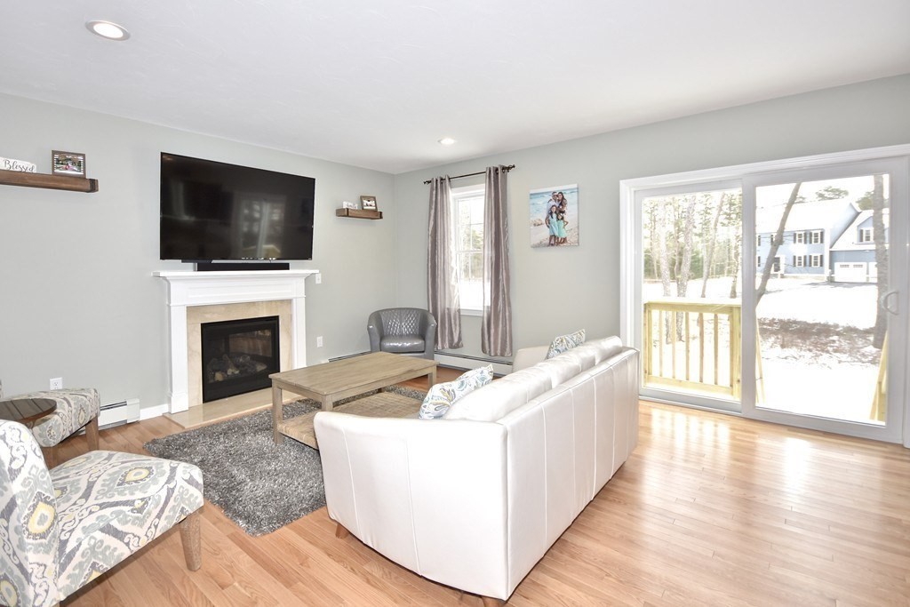 Lot 58-235 Forbes Road Rochester, MA 02770 - Photo 3 of 12 a living room with furniture a flat screen tv and a fireplace