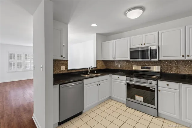a kitchen with granite countertop white cabinets and stainless steel appliances