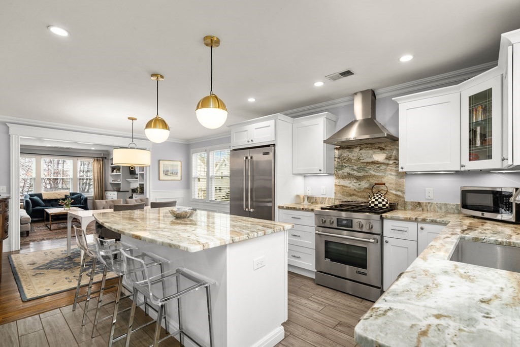 a kitchen with stainless steel appliances a stove a sink a oven a dining table and chairs