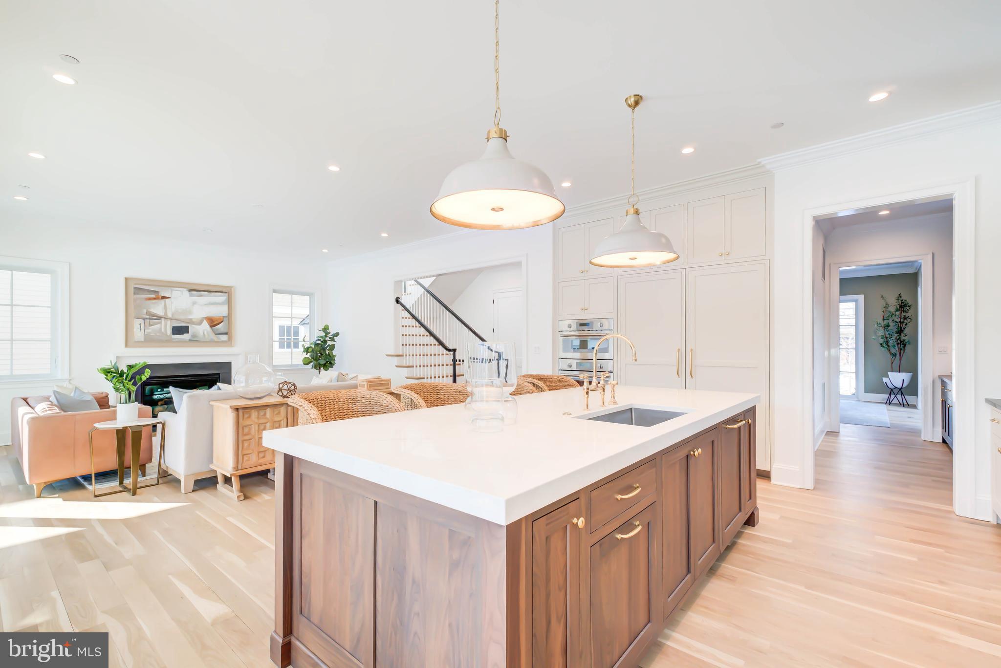 4422 Walsh Street Chevy Chase, MD 20815 - Photo 29 of 93 a room with a kitchen island a sink wooden floor and a chandelier
