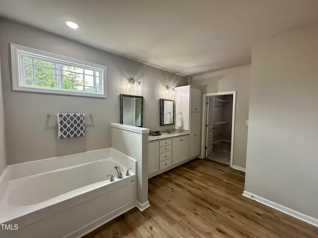 a bathroom with a tub sink and mirror