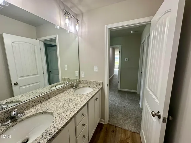 a bathroom with a granite countertop double vanity sink and a mirror