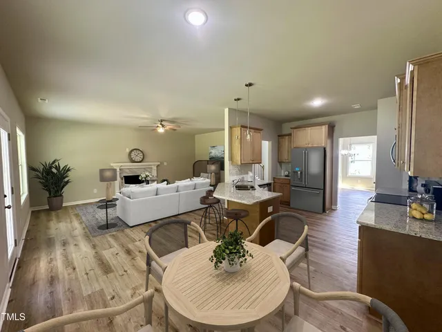 a living room with furniture and a dining table with wooden floor