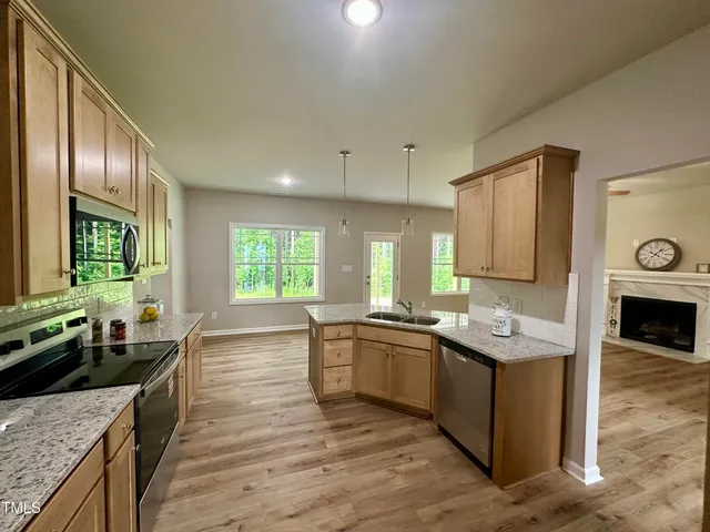 a large kitchen with stainless steel appliances granite countertop a sink stove and refrigerator