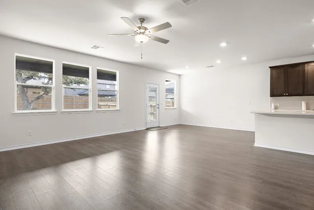 a view of an empty room with a window and wooden floor