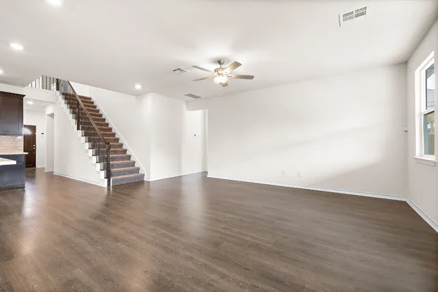 an empty room with wooden floor staircase and white walls