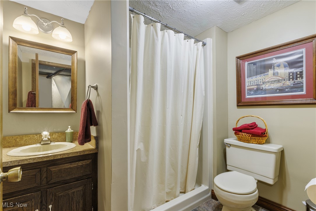 14816 Denman Road Wakeman, OH 44889 - Photo 27 of 41 Full bathroom with a stall shower, toilet, a textured ceiling, and vanity