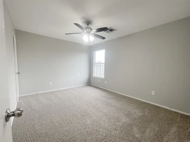 an empty room with windows and fan