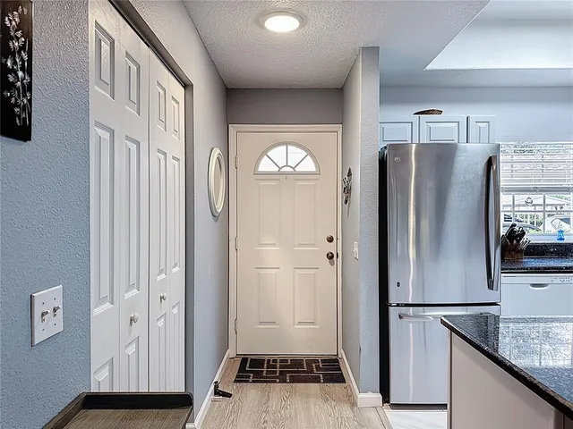 a view of a kitchen with refrigerator and wooden floor
