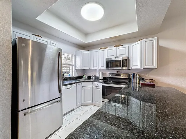 a kitchen with granite countertop a refrigerator stove top oven and sink