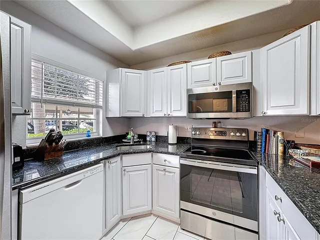 a kitchen with white cabinets and appliances