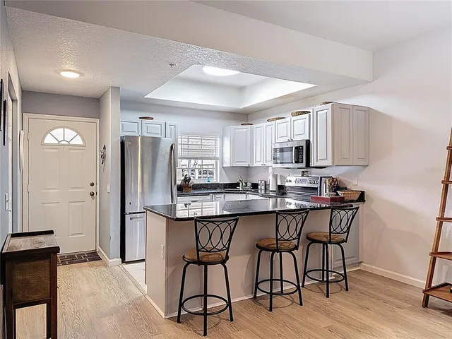 a kitchen with stainless steel appliances a dining table chairs refrigerator and sink