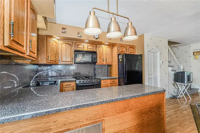 a kitchen with stainless steel appliances granite countertop a sink a stove and a wooden cabinets