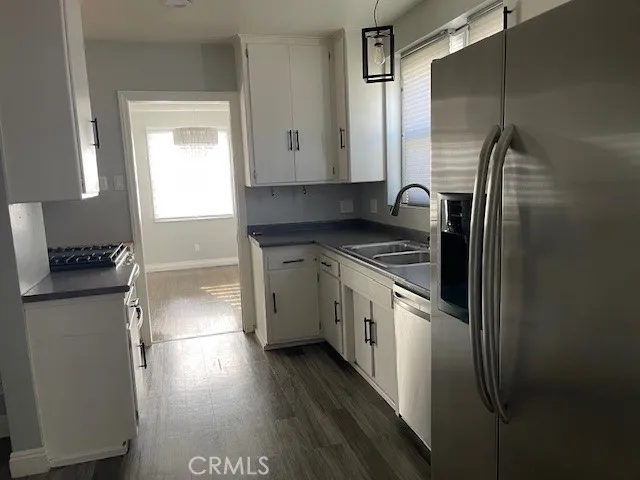 a kitchen with stainless steel appliances granite countertop a refrigerator a stove and a sink with wooden floor