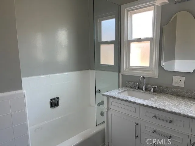 a bathroom with a granite countertop sink a mirror and a bathtub