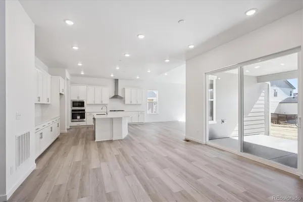 a large kitchen with stainless steel appliances lot of white cabinets and wooden floor