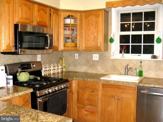 310 Greenwood Road Linthicum, MD 21090 - Photo 5 of 26 a kitchen with granite countertop a sink a stove and wooden cabinets