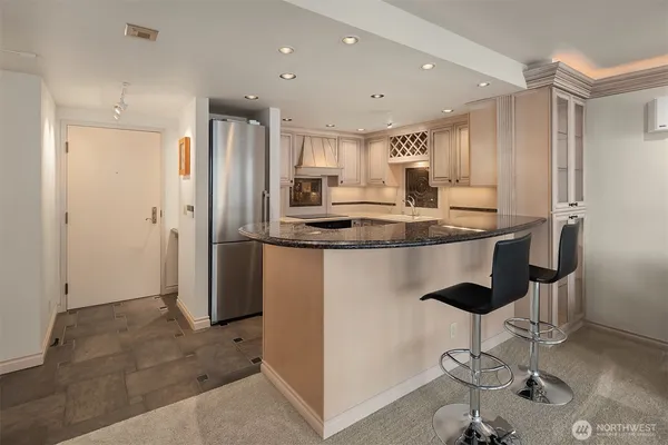 a kitchen with stainless steel appliances kitchen island granite countertop a refrigerator and a sink