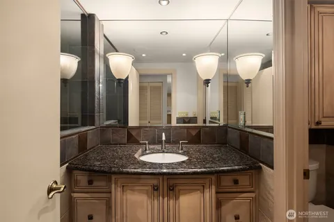 a bathroom with a granite countertop sink a light fixture and a mirror