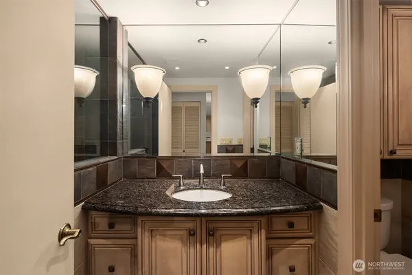 a bathroom with a granite countertop sink a light fixture and a mirror