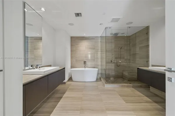 a bathroom with a tub sink mirror and shower