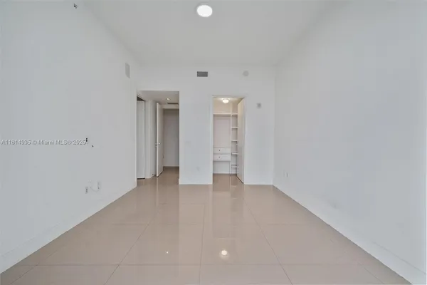 a view of an empty room with closet and a window