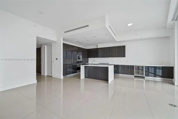 a large white kitchen with a sink and stainless steel appliances
