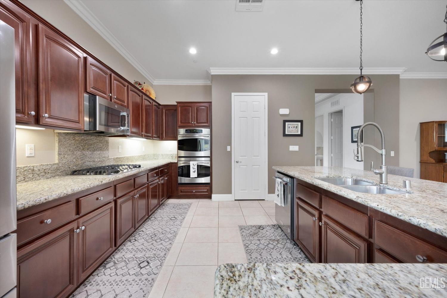 Undisclosed Address Bakersfield, CA 93306 - Photo 11 of 70 a large kitchen with stainless steel appliances granite countertop a stove a sink dishwasher and a refrigerator with wooden cabinets