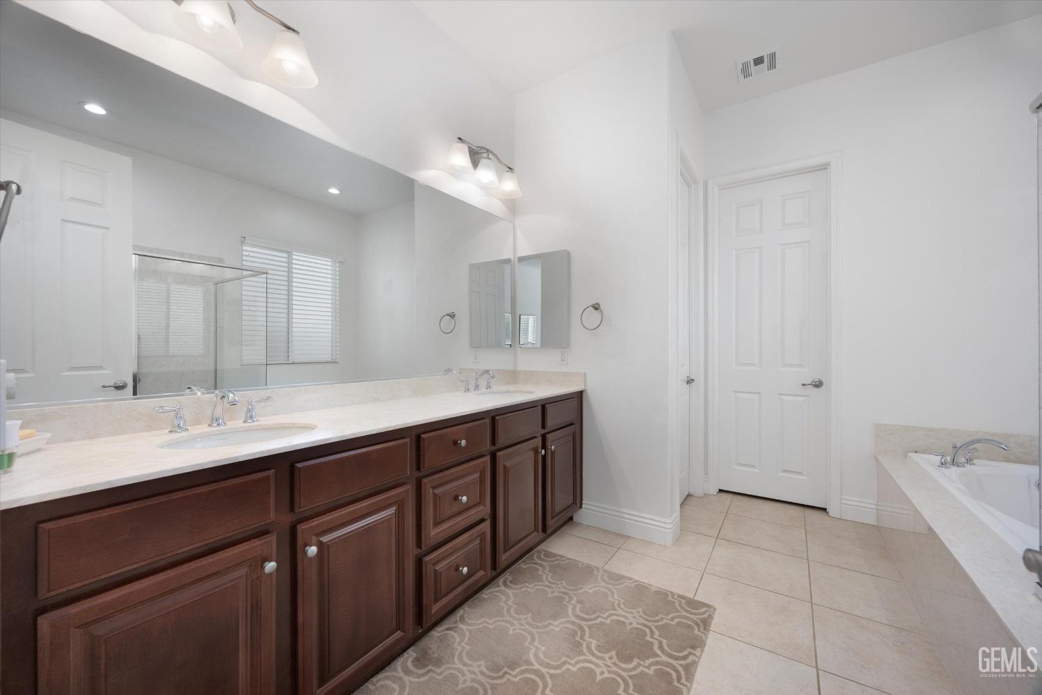Undisclosed Address Bakersfield, CA 93306 - Photo 20 of 70 a spacious bathroom with a double vanity sink a mirror and a bathtub