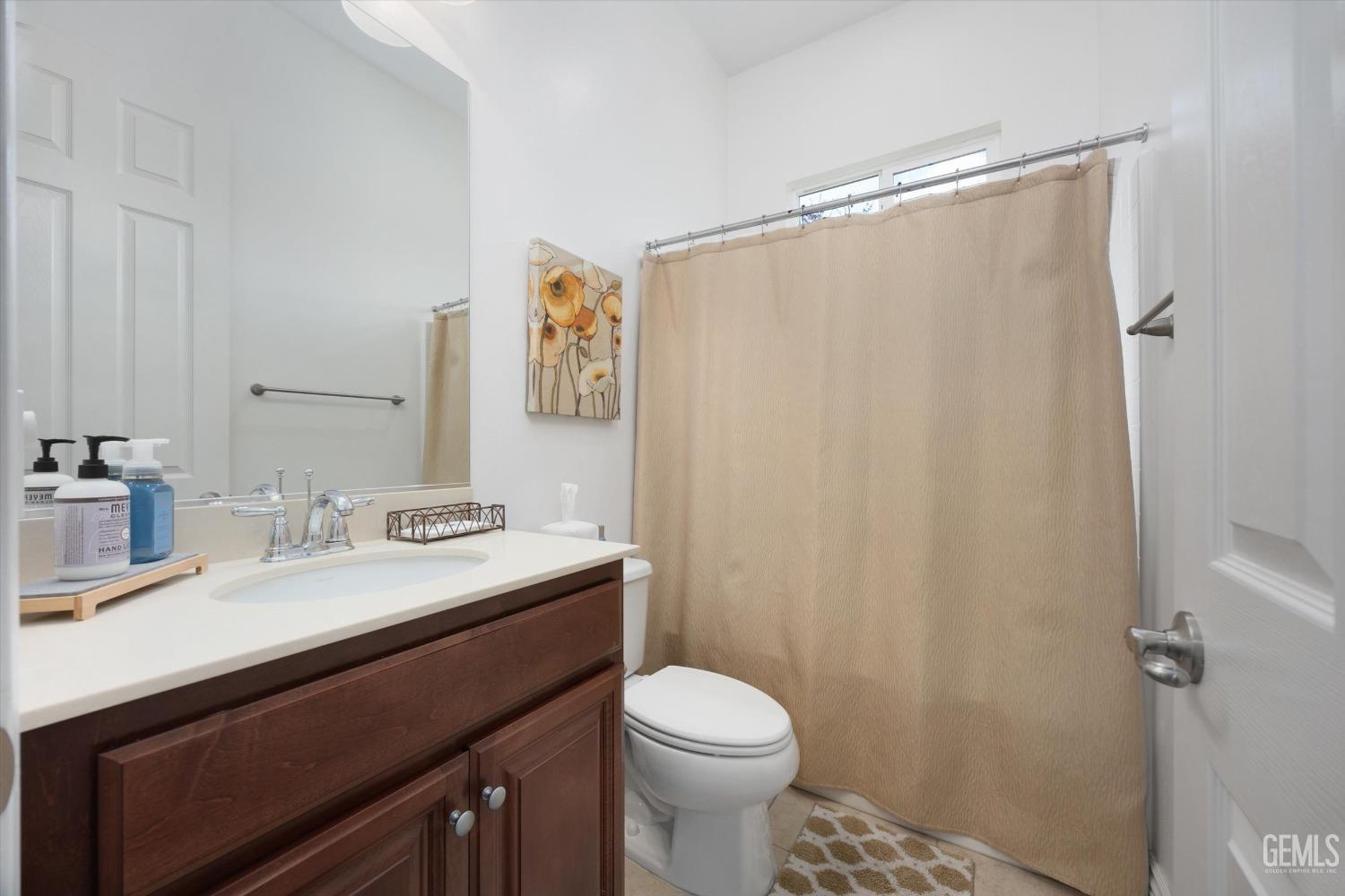 Undisclosed Address Bakersfield, CA 93306 - Photo 26 of 70 a bathroom with a sink a toilet a mirror and shower curtain